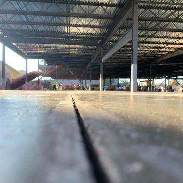 Control joint cut across a fresh warehouse slab the day of the pour
