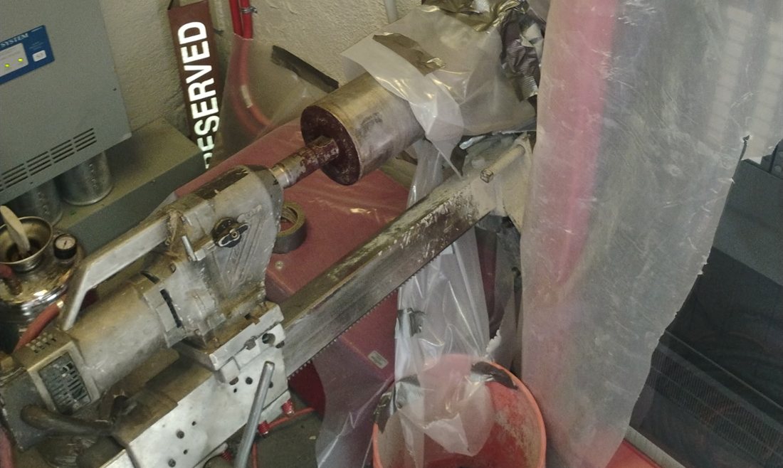 Core drill rig running horizontally behind containment plastic in a live plant room in Tempe
