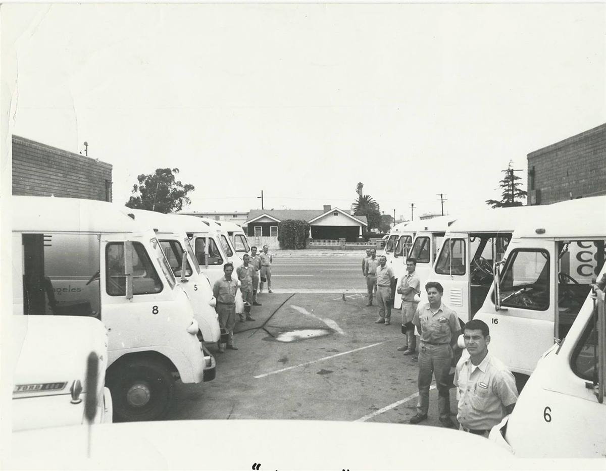The Concrete Coring Company crew standing with the numbered fleet of trucks in 1970