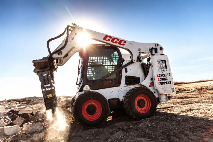 Concrete Coring Company skid steer breaking out concrete with a hydraulic breaker