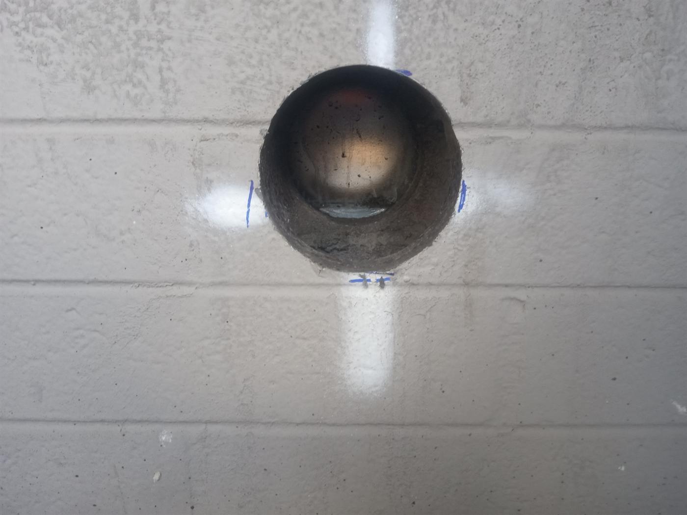 Clean 4-inch core hole drilled through a painted block wall at Cardinals Stadium in Glendale, Arizona