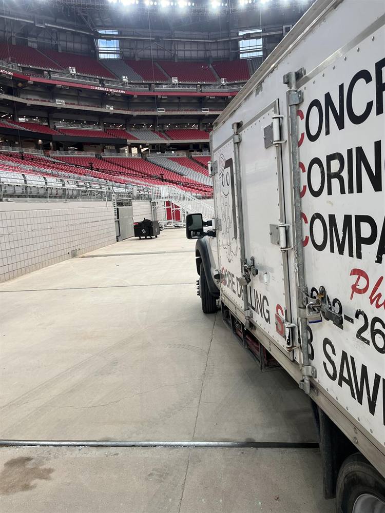Concrete Coring Company core drilling truck parked on the concourse at Cardinals Stadium in Glendale, Arizona, red seats behind
