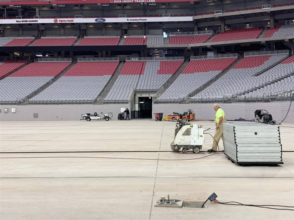 Slab sawing the concrete floor of Cardinals Stadium in Glendale with a walk-behind concrete saw, the seating bowl behind