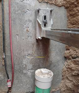 Core drill rig anchored to the curved wall of a precast manhole with the core location marked in yellow
