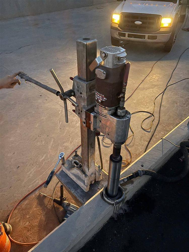 Core drill rig mounted on a custom fabricated bracket to drill straight down through the top of a concrete wall in Scottsdale