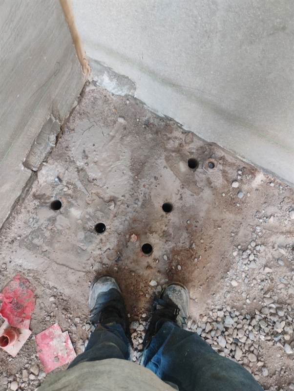 Five holes hand drilled into a concrete footer corner at Cosanti Commons in Scottsdale, laid out on the green line