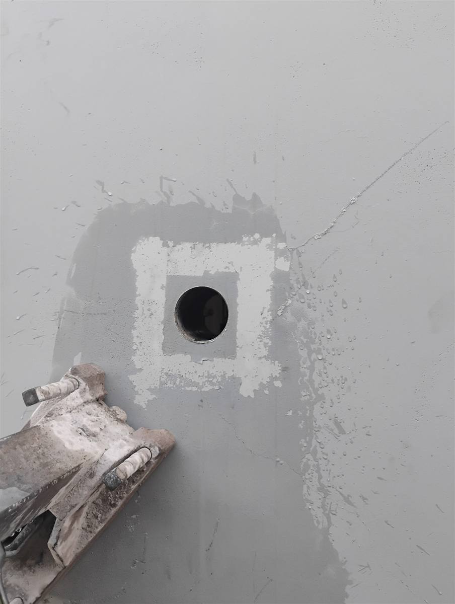 Clean round core drilled through the wall of a semi-truck plant in Tempe, the core rig base beside it
